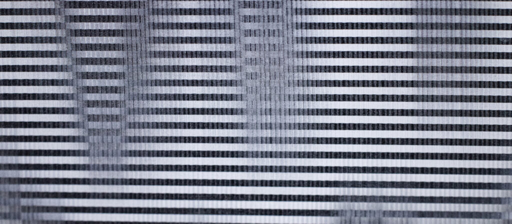 Detailansicht einer einzelnen Platte eines Lentikulardrucks mit schwarz-weißer Linienstruktur und sichtbarer Oberflächenwirkung.