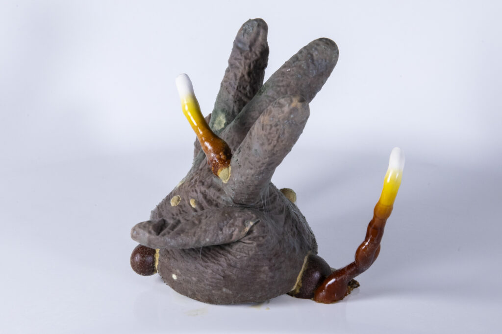 Objekt aus Latexhandschuh, aus dem myzelartige Strukturen hervortreten und das Material verformen.