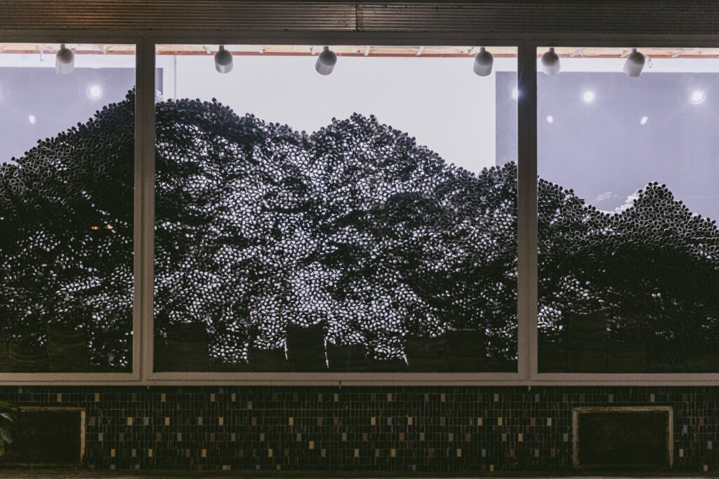 Detailansicht der Papierrollen mit sichtbaren Zwischenräumen, durch die Licht in die Struktur fällt.